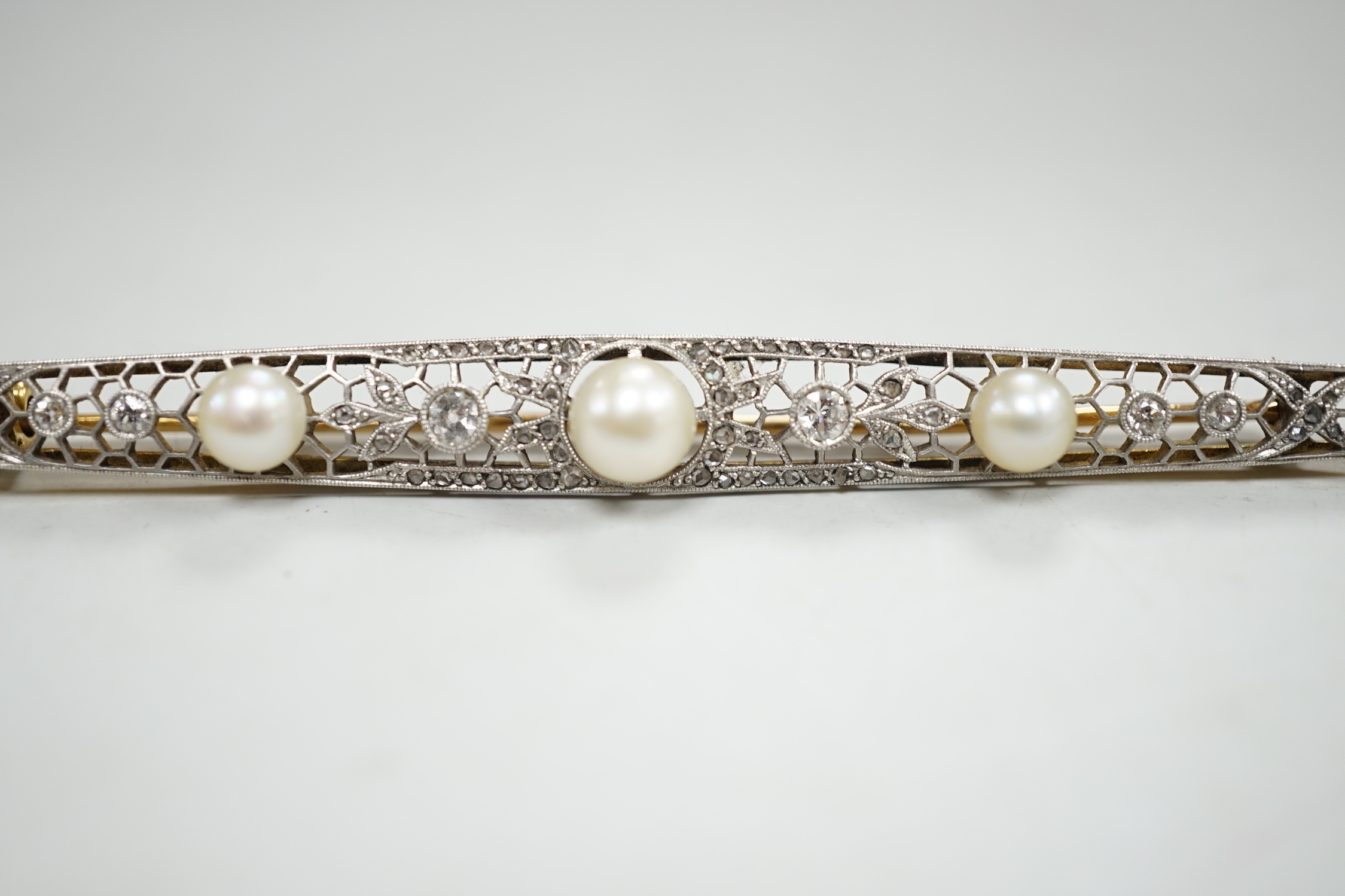 A Belle Epoque pierced yellow and white metal, cultured? pearl and diamond set bar brooch, 84mm, gross weight 10 grams, in fitted leather box.